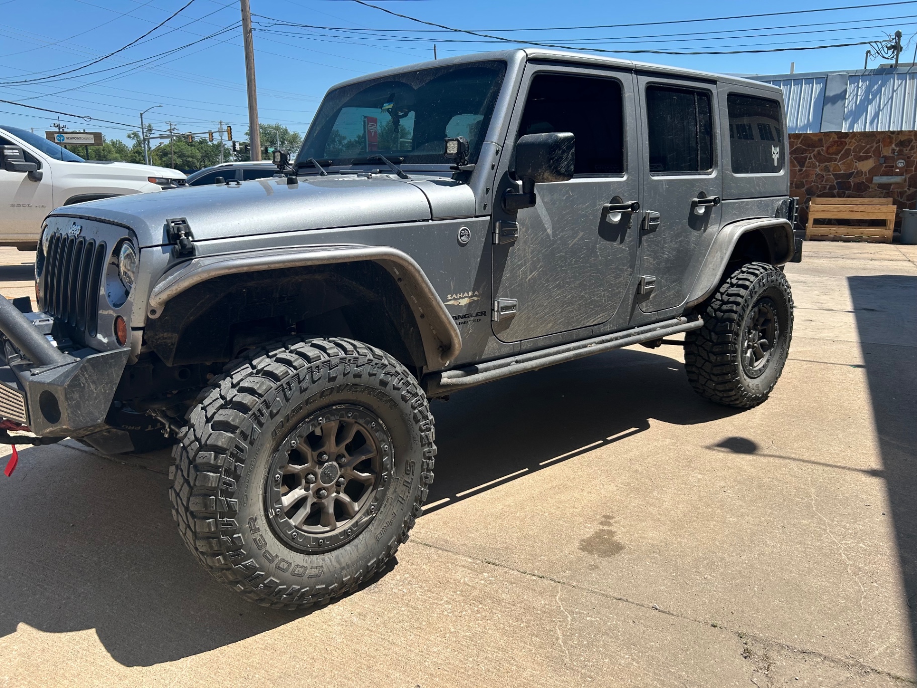 Silver Jeep Wrangler Sahara lifted on 37s with window tint Ponca City