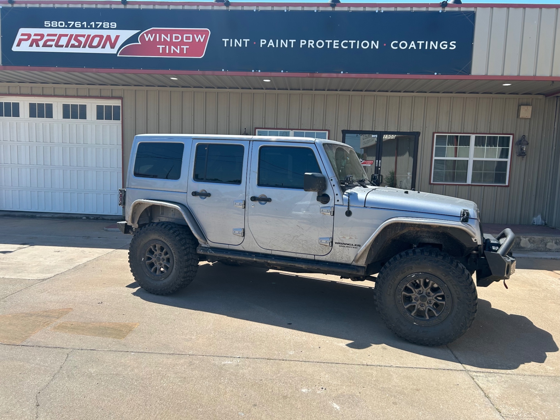 Lifted silver Jeep Wrangler Unlimited with dark window tint Ponca City