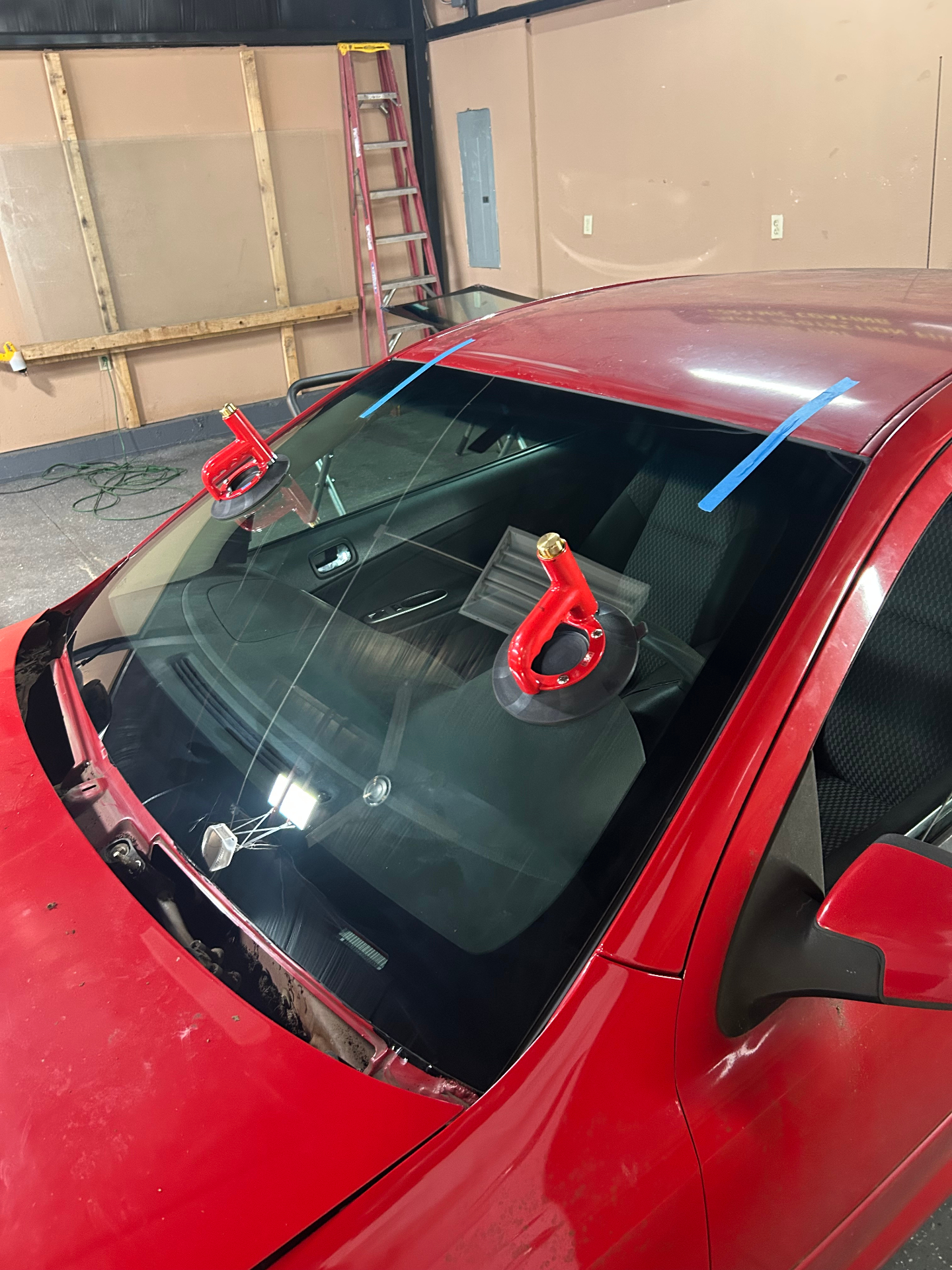 Red coupe with windshield installation in progress